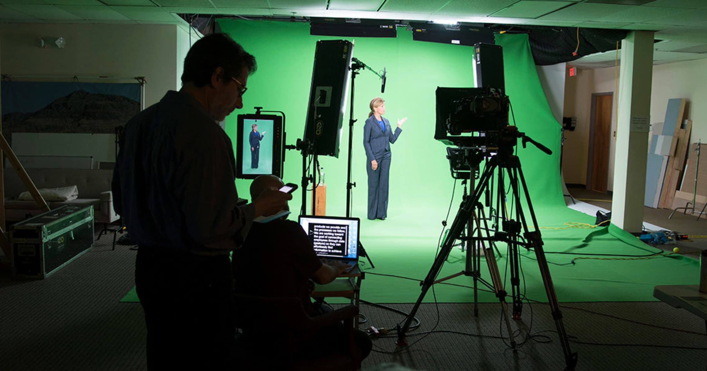 a woman standing in front of a green screen for a film crew